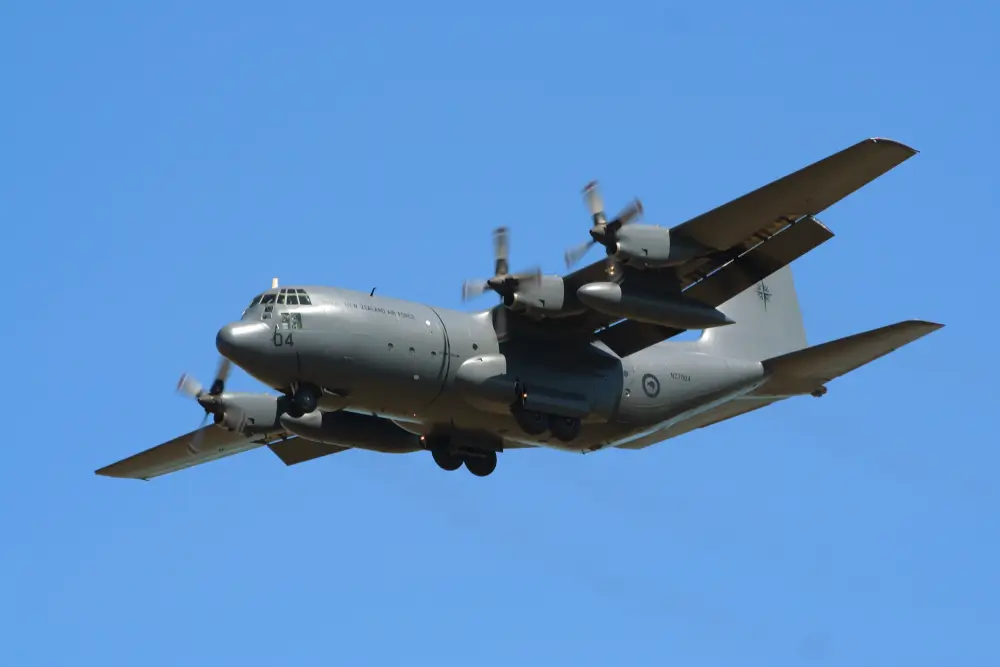 C-130 Hercules NZ Air Force transport aircraft flying in a clear blue sky for humanitarian and defense missions.