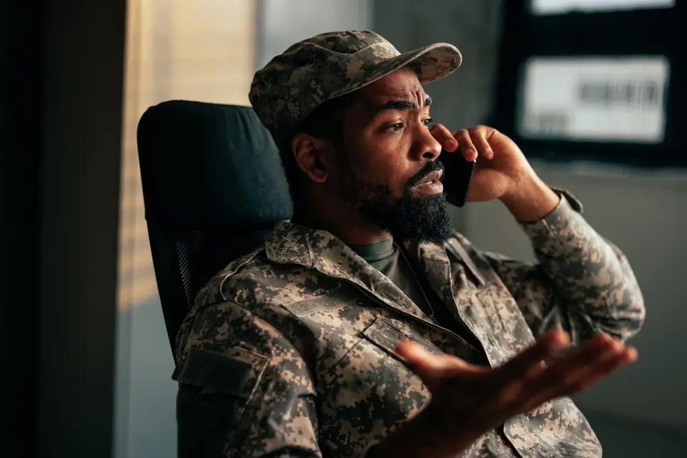Military officer in camouflage uniform gesturing on a phone call, demonstrating leadership and mentoring for the army.