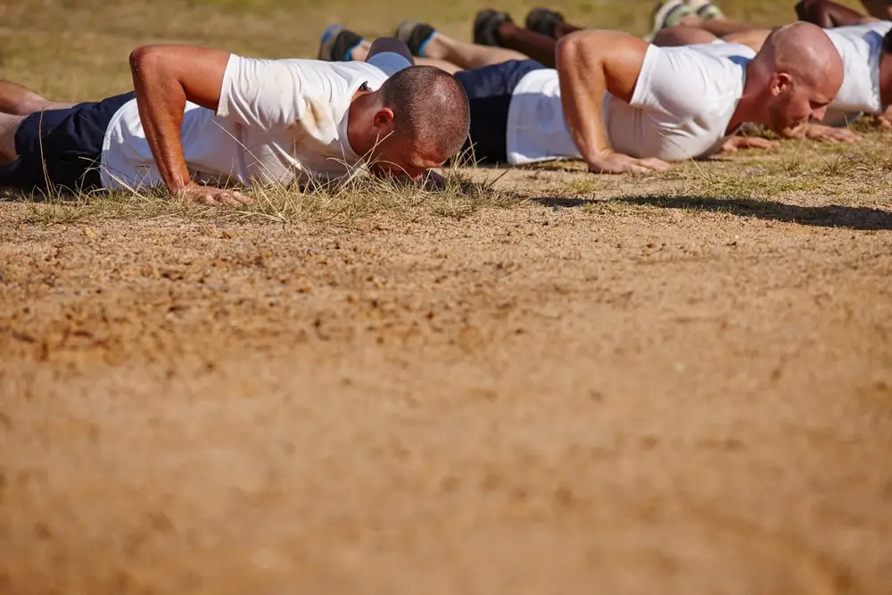 New Zealand Army recruits performing push-ups outdoors during a military physical fitness test.