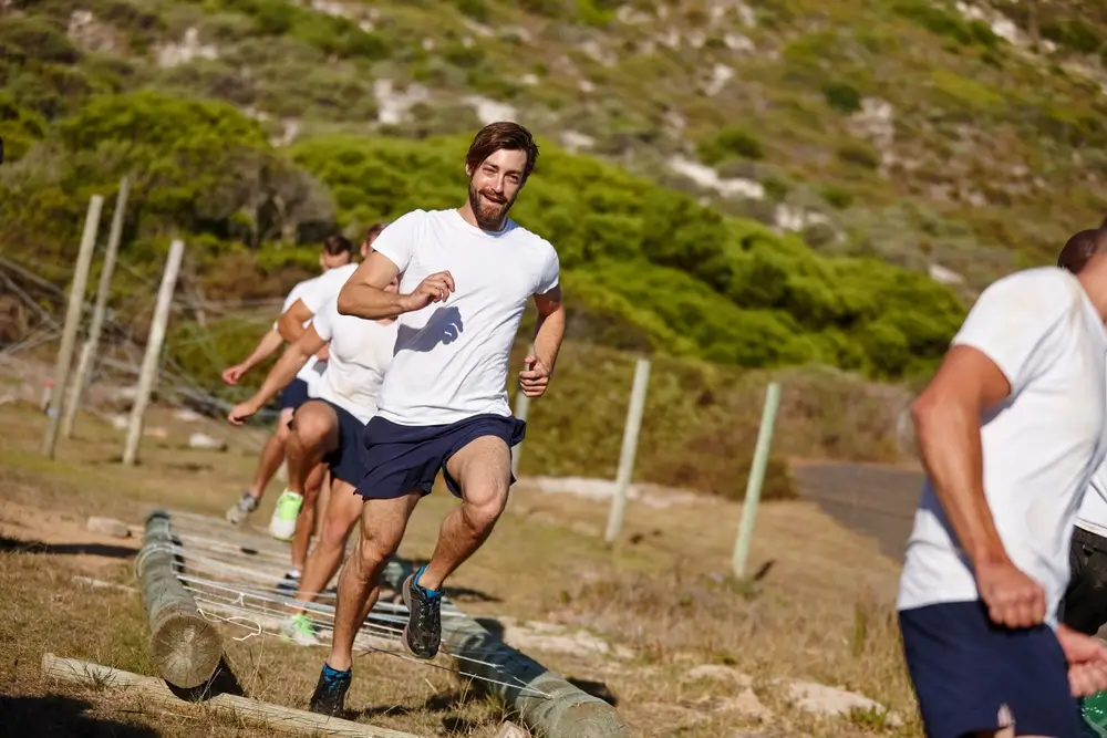 Candidates running through an outdoor training course during a military recruitment fitness test assessment.