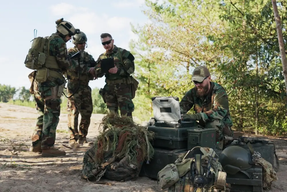New Zealand Army soldiers using digital equipment and tablets during a military training exercise in the field.