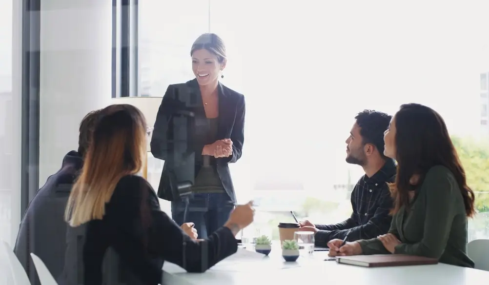 Professional woman in business attire leading a meeting in a modern office, showcasing civilian expertise.