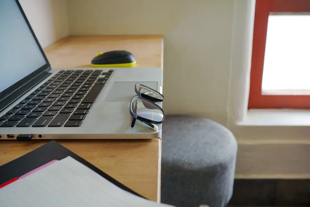 Organized office desk study area with a laptop and glasses, providing a focused environment for online assessments.