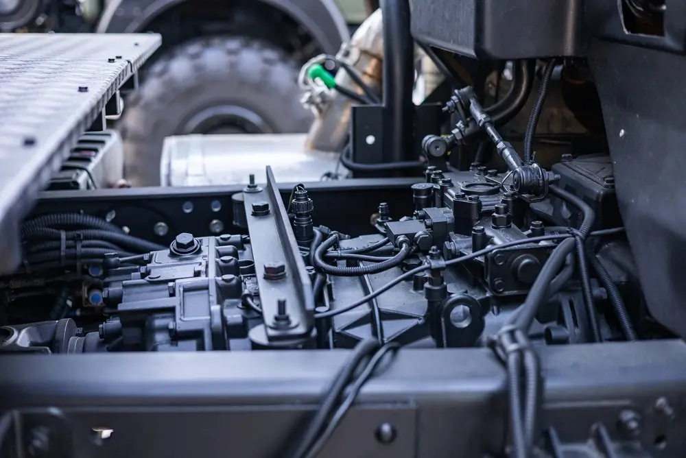 Detailed view of a military vehicle engine and complex mechanical parts maintained by an army mechanic.