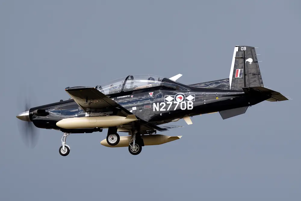 T-6C Texan II military training aircraft with landing gear down, used for air force pilot instruction.