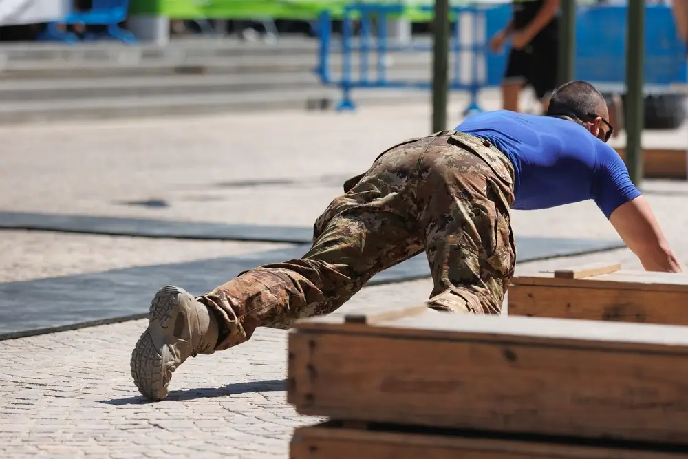 Soldier in camouflage gear performing a fitness assessment during military physical training outdoors.
