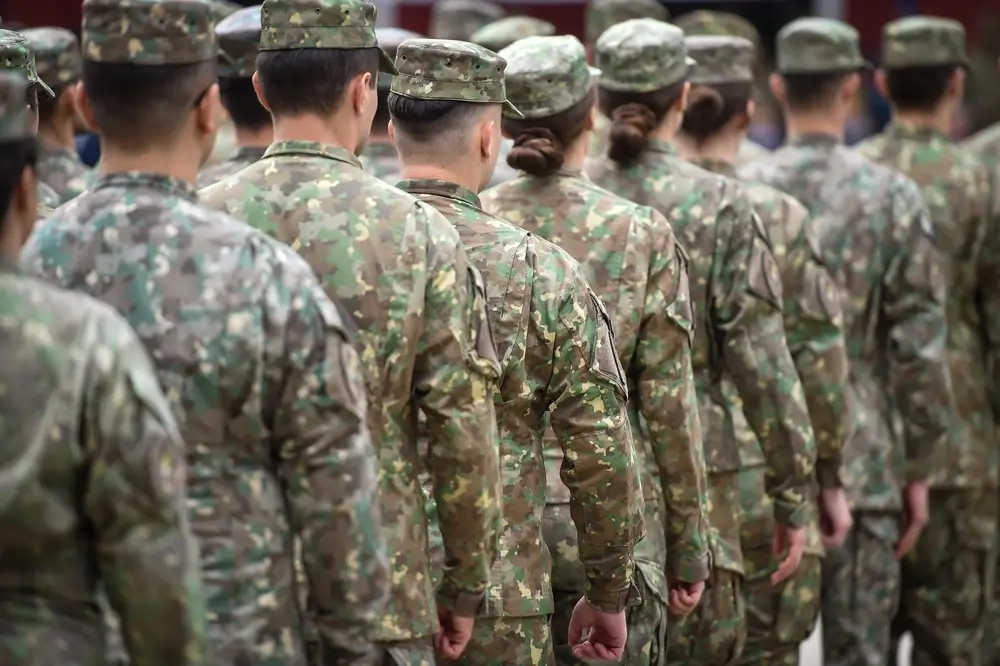 Army soldiers in camouflage uniforms standing in formation during a military parade at a basic training camp.