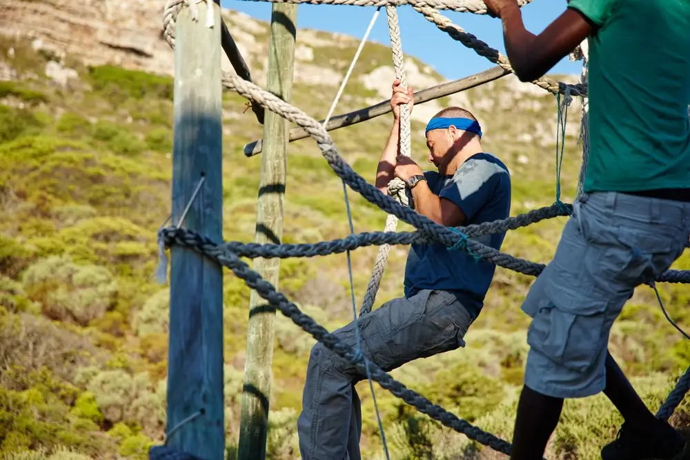 Navy sailors during physical training, navigating an outdoor rope obstacle course during their basic training.