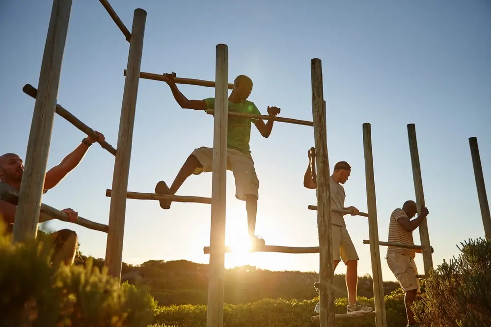 Recruits navigate a wooden obstacle course during NZ army military training at sunset.