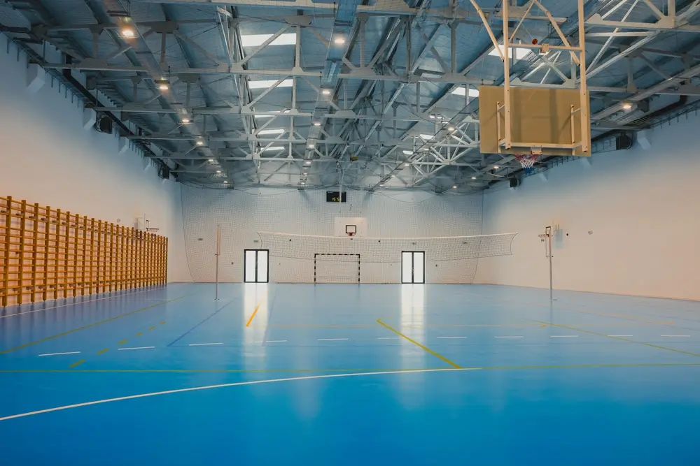 Bright sports hall interior gymnasium featuring a blue sports hall gym floor with marked lines for fitness testing.