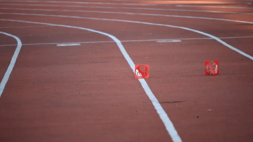 Orange cones on a fitness running track marking the 20-meter shuttle distance for a beep test.