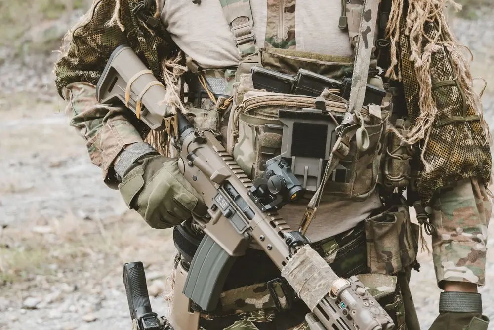 Soldier wearing tactical combat gear and webbing while holding a rifle for a military land combat fitness test.